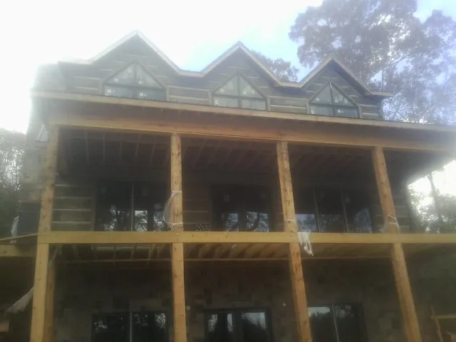 Dormers and porch framing on a large log home under construction — Roof Coating work by our crew in Ulysses