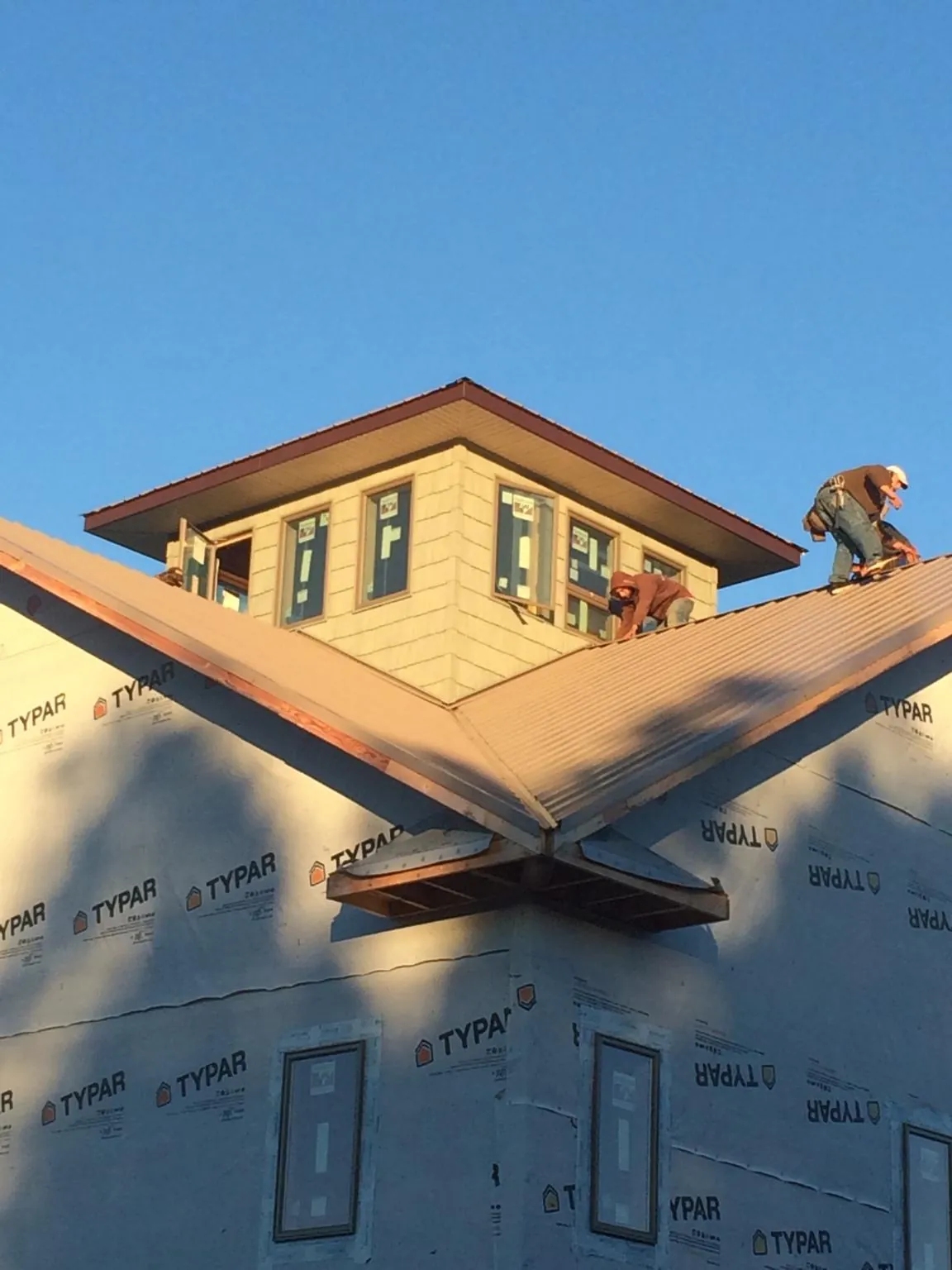 Roofers working around a rooftop cupola on a new metal roof at sunset — Roof Waterproofing in Ulysses by Roofing Brothers